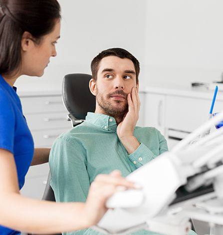 Man in dental chair holding cheek