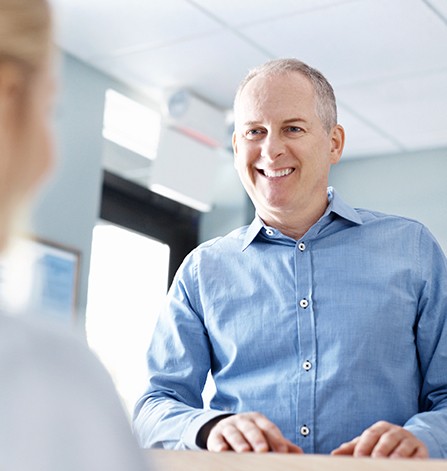 Smiling man at dental office reception desk